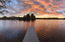 Stunning golden hour sunset over the calm waters of the Northwoods, viewed from the shoreline of our Eagle River lakefront property.